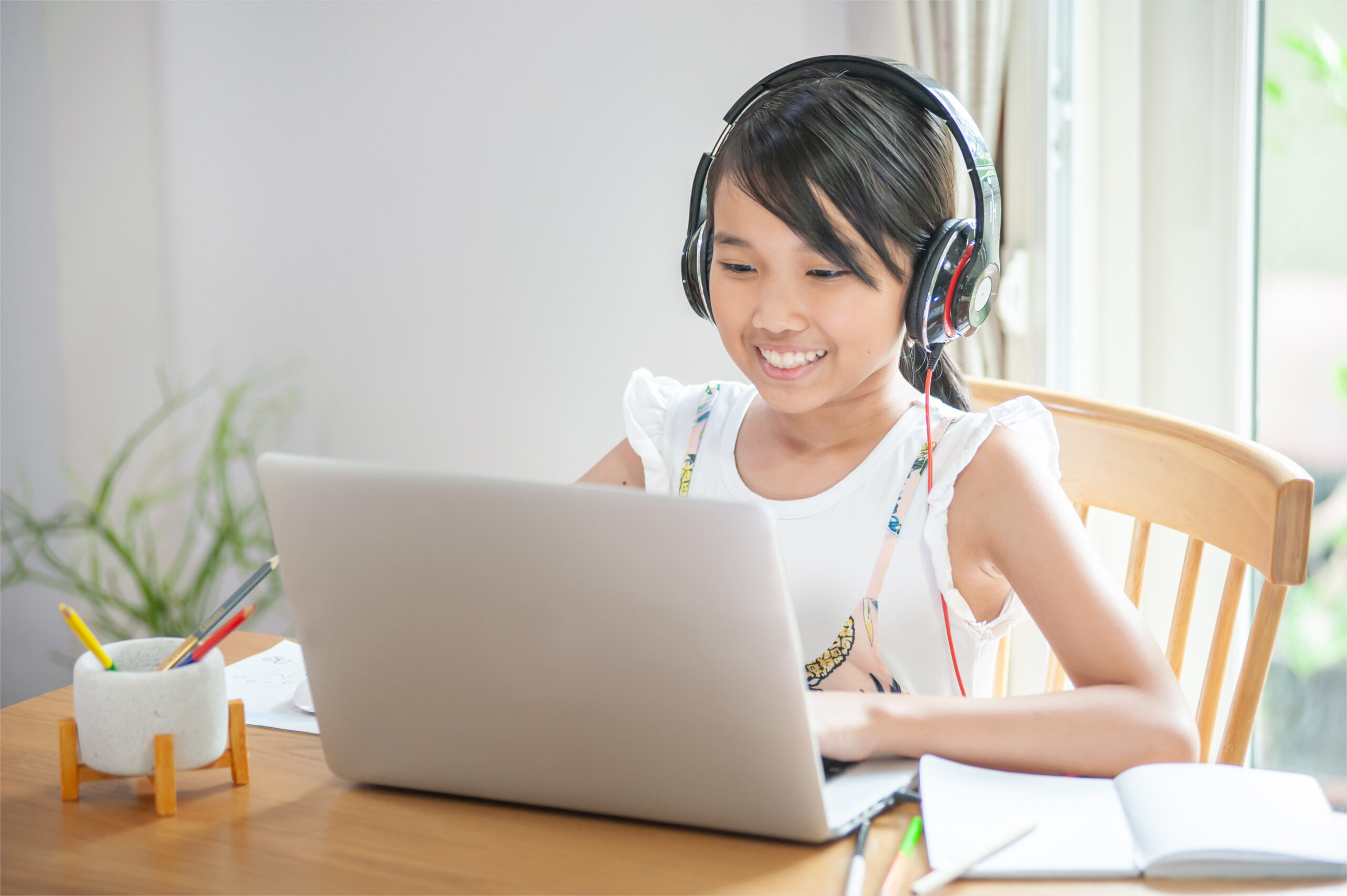 Smiling little girl using laptop to learn online at home